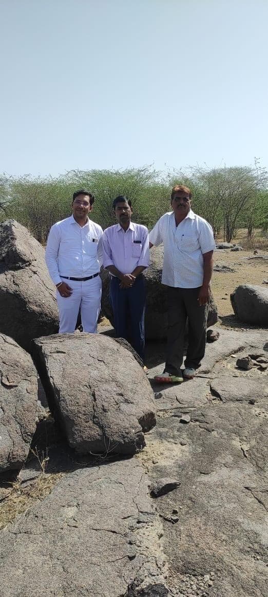 Three men standing on rocks at a granite mine