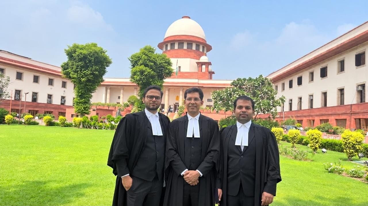Three advocates in gowns in front of the Supreme Court of India