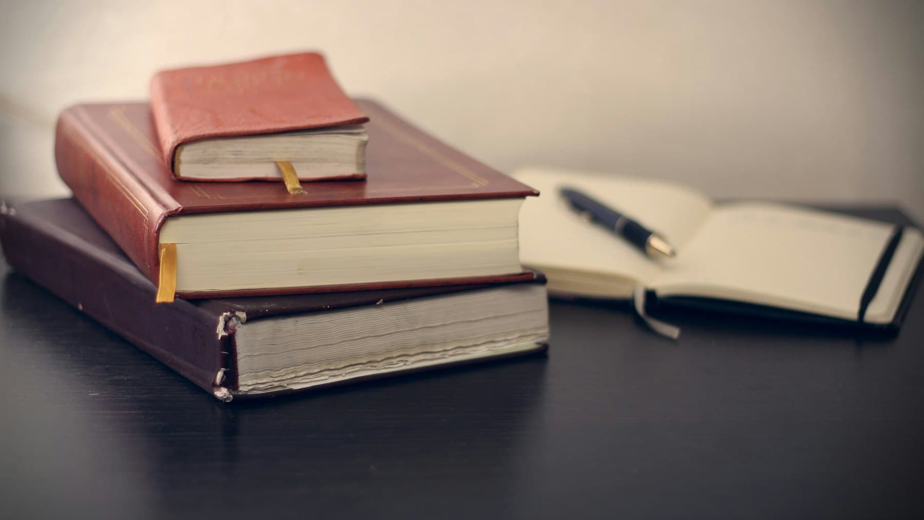 A fountain pen resting on leather-bound books
